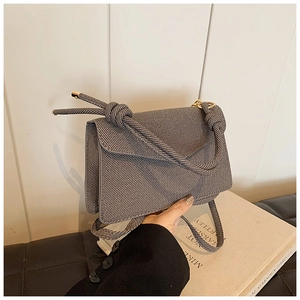 Détail du sac bandoulière en tissu gris avec bandoulière à nœuds et accents dorés