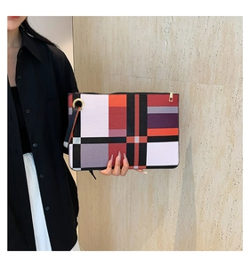 Detail of colorful geometric pattern envelope clutch with wrist strap and metal zipper