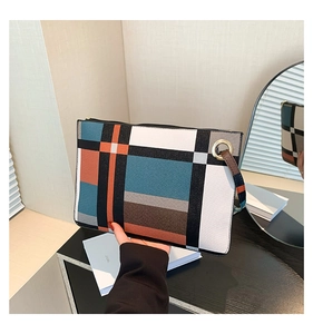 Detail of color-block geometric grid envelope clutch with metal ring and wristlet strap