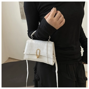 Close-up of a white mini bag with crocodile texture and golden metal oval hardware