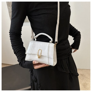 Detailed view of white crocodile pattern handbag with golden oval metal lock clasp
