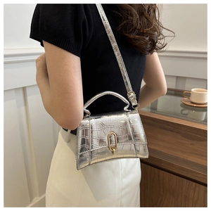 Detail of silver crocodile-embossed mini handbag with metallic finish and curved base