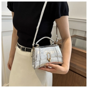 Detail of silver crocodile pattern mini handbag with gold oval lock and metallic finish