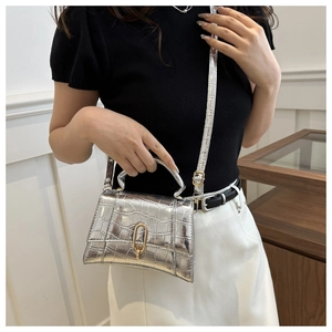 Detail of silver crocodile-embossed leather handbag with metallic finish and gold U-shaped lock