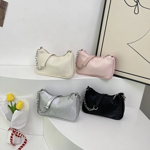 Stylish solid color underarm bags with metal chain straps in a minimalist setting