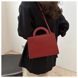 Minimalist burgundy square crossbody bag with hollow handle shown on model
