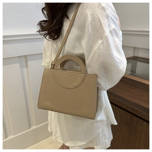 Detail of minimalist rectangular PU leather handbag with unique circular hollow handle