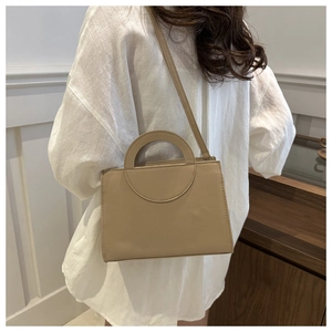 Beige PU leather crossbody bag with circular cutout handle worn by a model in casual setting