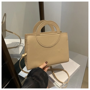 Detail of beige PU leather crossbody bag with integrated semi-circular handle and stitching