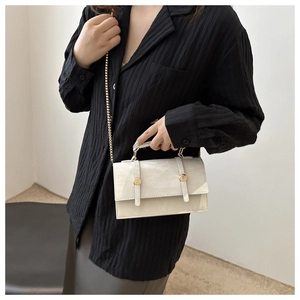 Detail of white glossy mini square bag with golden twist locks and fine chain strap