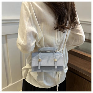 Détail du sac sous les bras bleu clair avec chaîne dorée et texture plissée