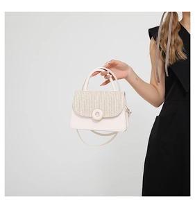 Close-up of cream square bag featuring a woven flap and decorative round donut buckle