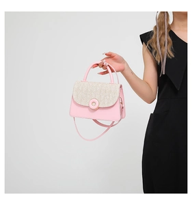 Detail of pink leather and beige woven handbag with gold ring buckle on a black dress