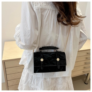 Détail du sac bandoulière en velours noir plissé avec chaîne dorée et boucles
