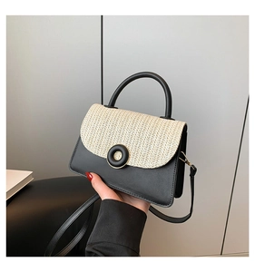 Detail of crossbody bag featuring black leather, beige woven straw and gold buckle hardware
