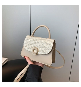 Detail showing herringbone straw texture and resin buckle on the cream crossbody bag