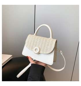 Detailed view of woven straw flap and white faux leather square bag with round buckle