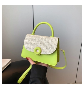 Detail of hand-held mini square bag with grass green body and cream straw woven flap