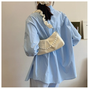 Detail view of a cream pleated shoulder bag with a pearl chain strap and soft fabric strap