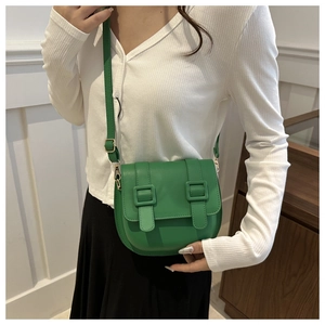 Close-up of green leather crossbody saddle bag with gold hardware worn by a model
