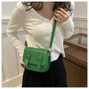 Green leather saddle bag shown on model featuring double straps and gold hardware