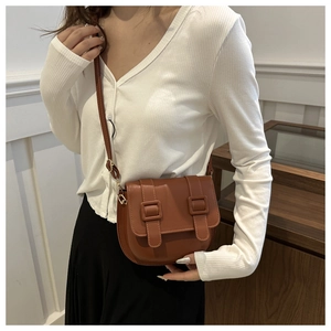 Close-up of a brown PU leather saddle bag with flap closure and adjustable strap