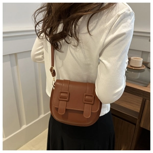Detailed back view of a brown saddle bag featuring dual decorative straps and gold hardware