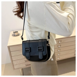 Close-up of black retro saddle bag with double strap buckles and adjustable shoulder strap