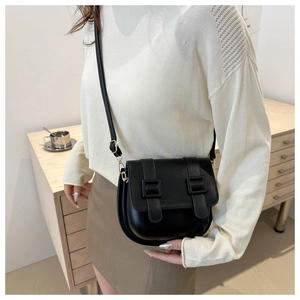Crossbody saddle bag in matte black with square buckles shown on a female model