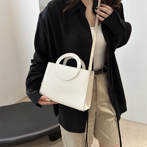 Minimalist cream white square crossbody bag with unique round handle and slim strap
