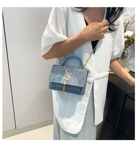 Detail of blue matte leather crossbody bag with golden SS logo and tassel accent