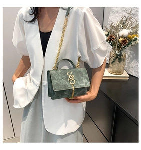 Detail of dark green textured crossbody bag with golden S-buckle and elegant chain strap
