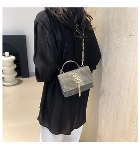 Detail of grey suede shoulder bag with gold chain strap and circular metal handle