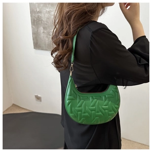 Detail of green hobo bag featuring embossed geometric texture and gold metal hooks