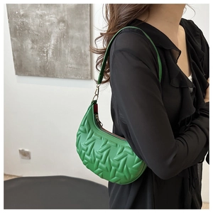 Close-up of green moon bag featuring embossed geometric patterns and gold metal hooks