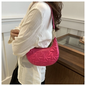Close-up of geometric quilted texture on rose red crescent shoulder bag with gold hardware