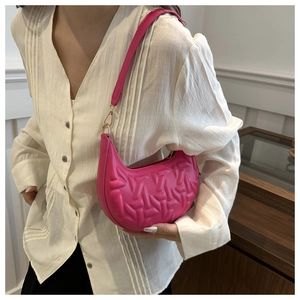 Close-up of rose red crescent shoulder bag with geometric quilted texture and gold hooks