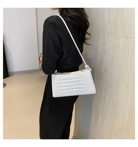 Detail of white crocodile embossed faux leather underarm bag with gold metal buckle