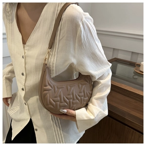 Detailed view of brown crescent shoulder bag with geometric quilted pattern and gold buckle