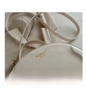 Close-up of white semi-circular PU leather bag with golden Fashion Bags logo text