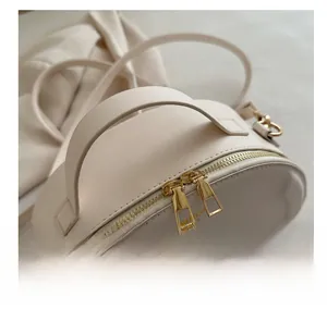 Detailed close-up of ivory cream handbag with double zippers and soft handle grip