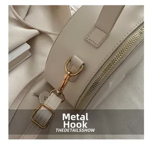 Detailed macro of golden metal hook and zip closure on cream leather shoulder bag