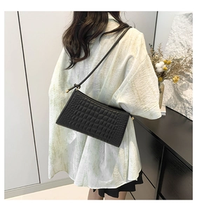 Detailed view of black crocodile pattern shoulder bag with elegant gold metal hardware