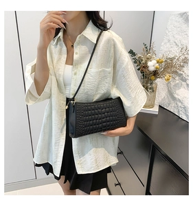 Modern black crocodile pattern shoulder bag shown styled on a model in a minimalist room