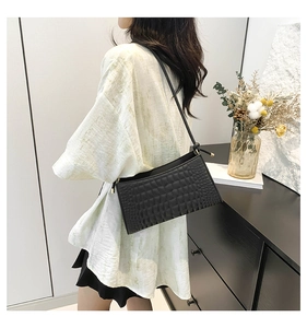 Close-up of black crocodile pattern leather underarm bag featuring elegant gold buckles