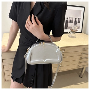 Silberne Halbmond-Schultertasche mit goldenen Details zu einem schwarzen Kleid und Deko