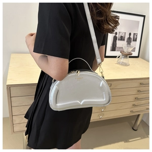 Silberne Mondsichel-Tasche mit Metallic-Finish und goldener Hardware in edlem Lifestyle-Ambiente