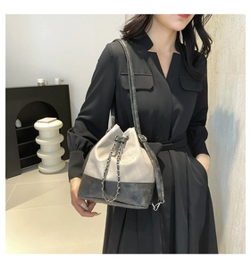 Detail of grey bucket bag showing chain drawstring and matte leather texture on model