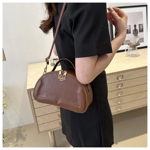 Detail of a brown half-moon faux leather handbag with a top handle and gold zipper