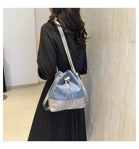 Detail of blue and silver bucket backpack featuring chain accent and drawstring closure